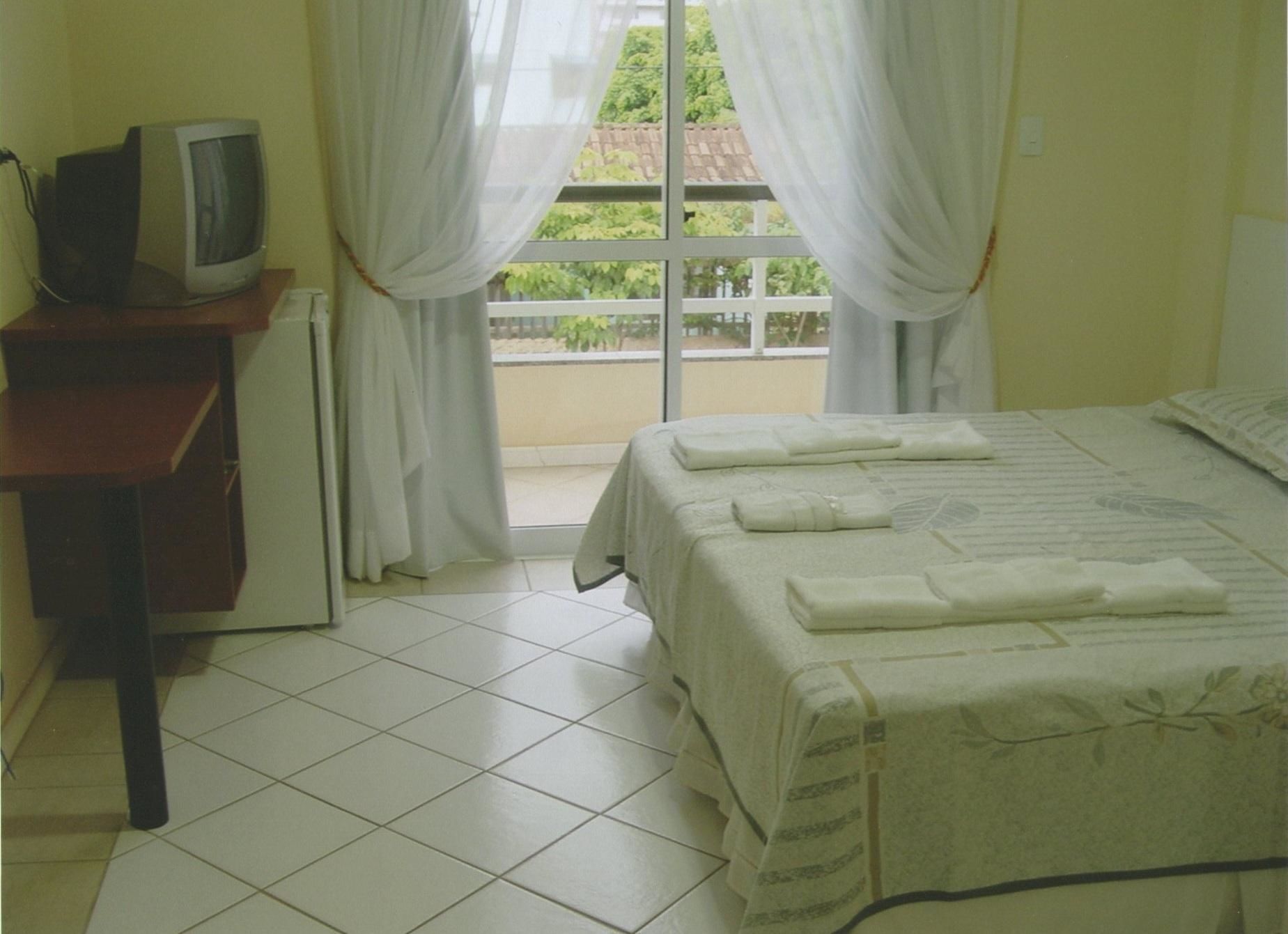 Habitación de hotel con cama, televisor en un escritorio y vistas a zonas verdes.