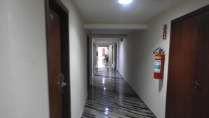 Un pasillo con un extintor de incendios fijado en la pared, una puerta a la izquierda y otra a la derecha.