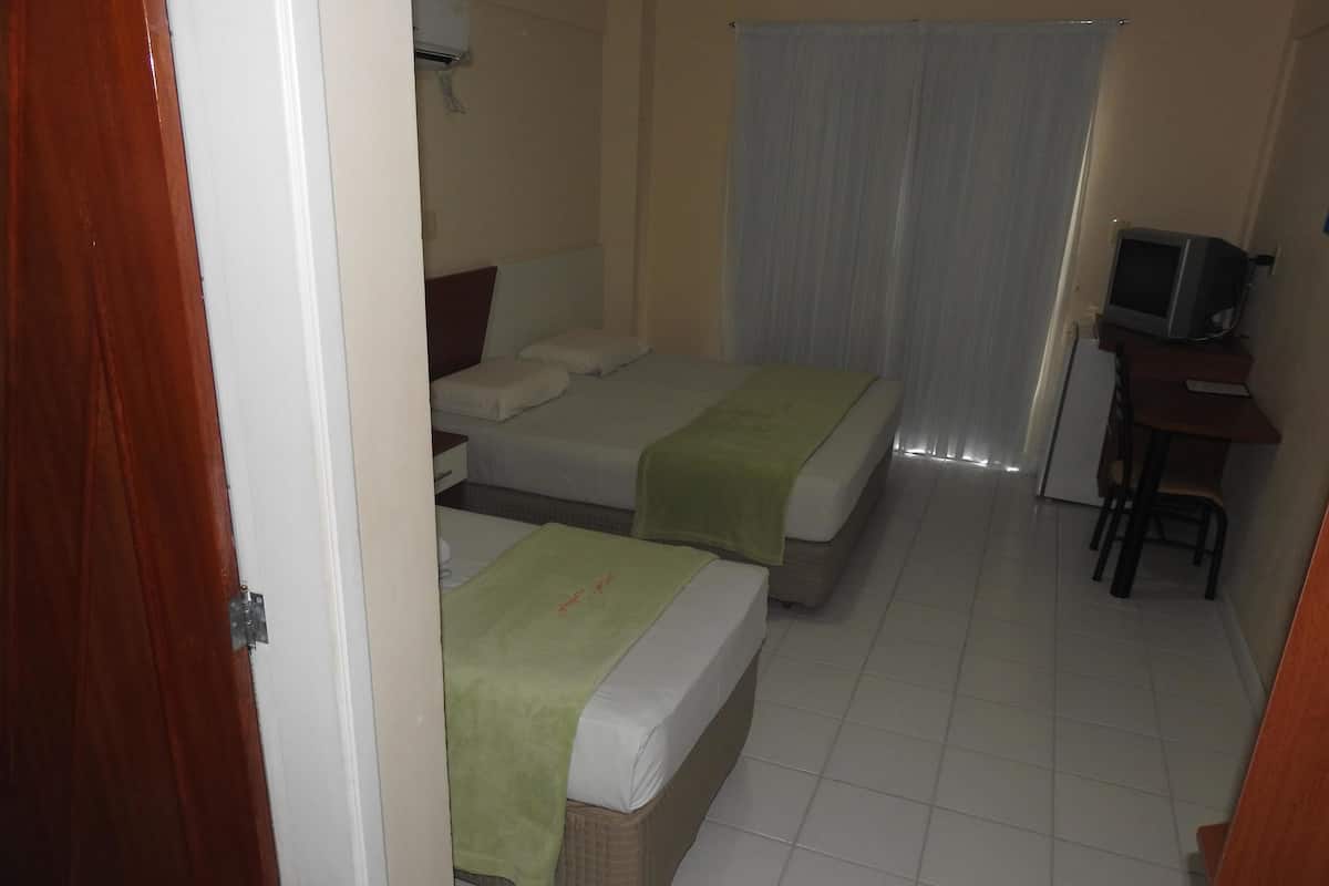 Habitación de hotel con dos camas, un escritorio con televisor y una ventana con cortinas.