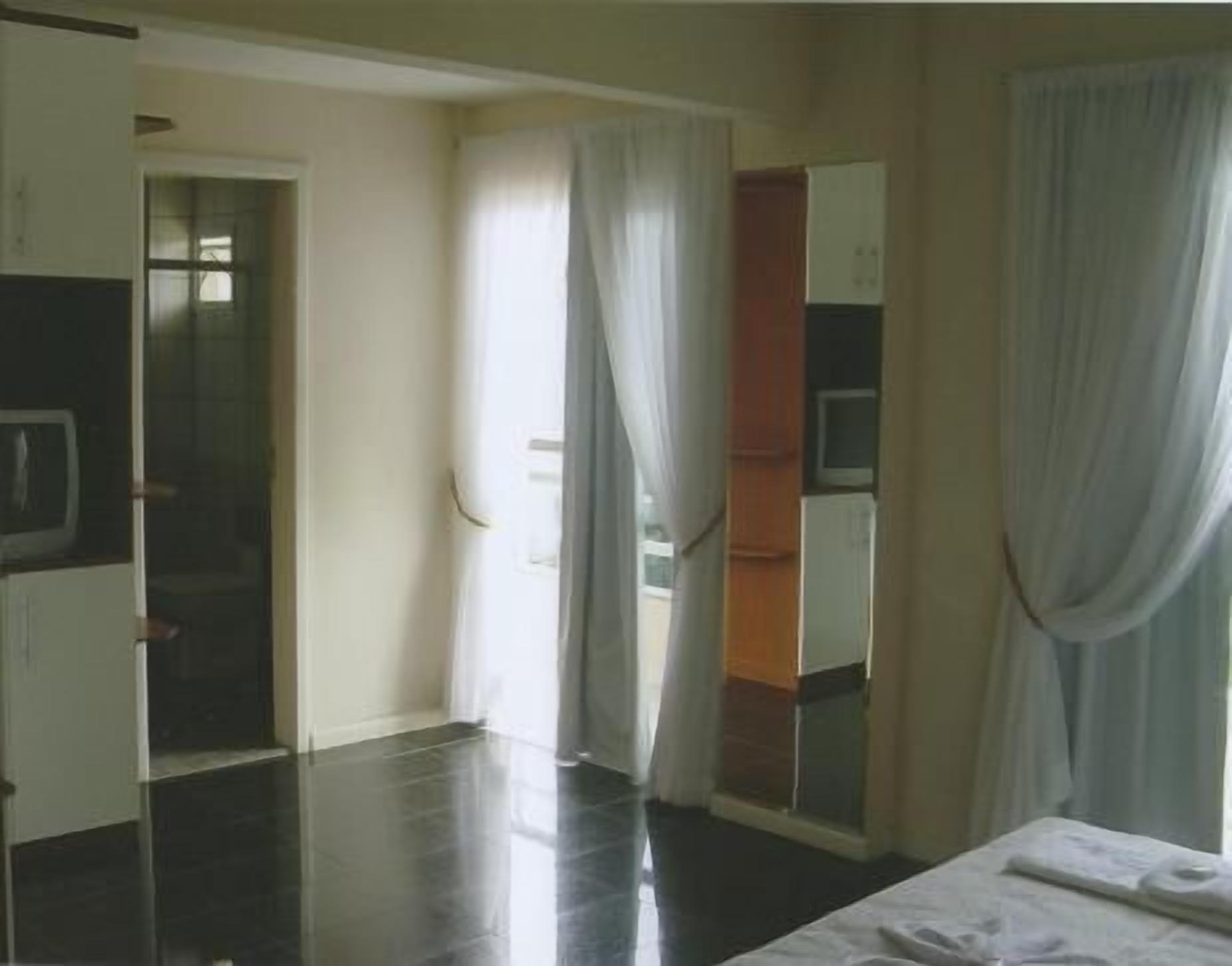 Ett hotellrum med en säng, en tv, en spegel och en dörr som leder till ett annat rum.