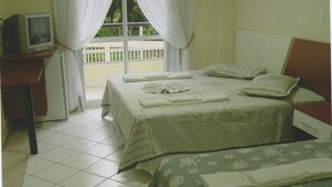 Una habitación con dos camas, un televisor sobre un escritorio y una ventana con cortinas.