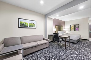 Een hotelkamer met een bank, bureau, stoel en bed.