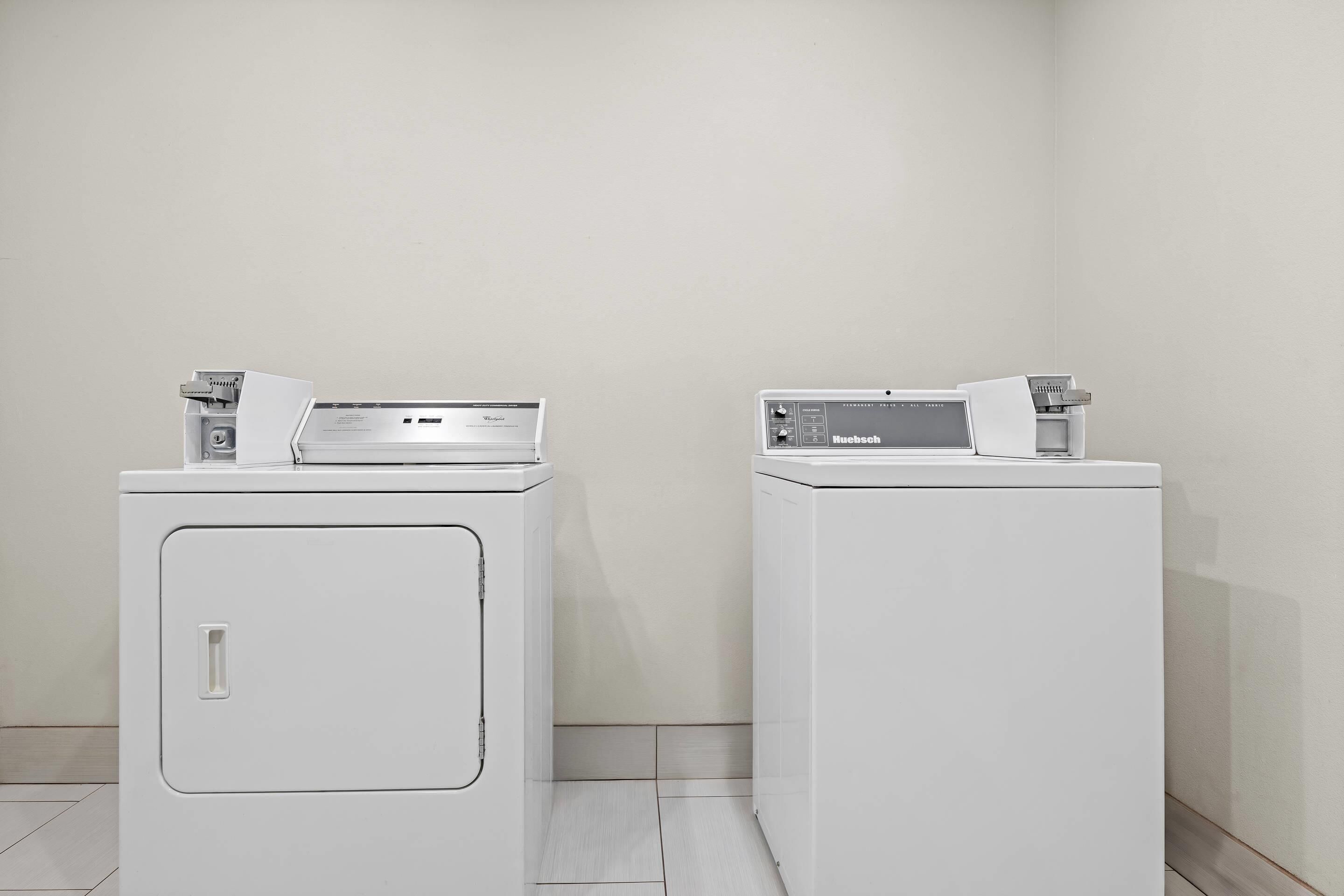 Twee witte voorladers in een hoek, met een effen muur en betegelde vloer.