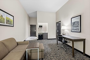 Une chambre d’hôtel équipée d’un canapé, d’un bureau, d’une chaise, d’une petite kitchenette et d’un lit.