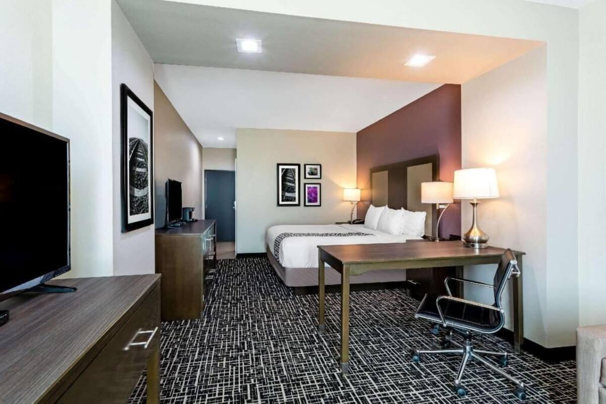 Een hotelkamer met een bed, bureau, stoel, televisie en kunstwerken aan de wanden.