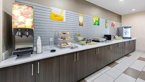 Un espace de petit-déjeuner en libre-service comprenant une machine à café, un distributeur de boissons et une variété d’aliments.