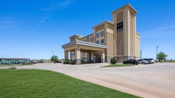 A hotel with a central tower, a covered entrance, and a parking lot.