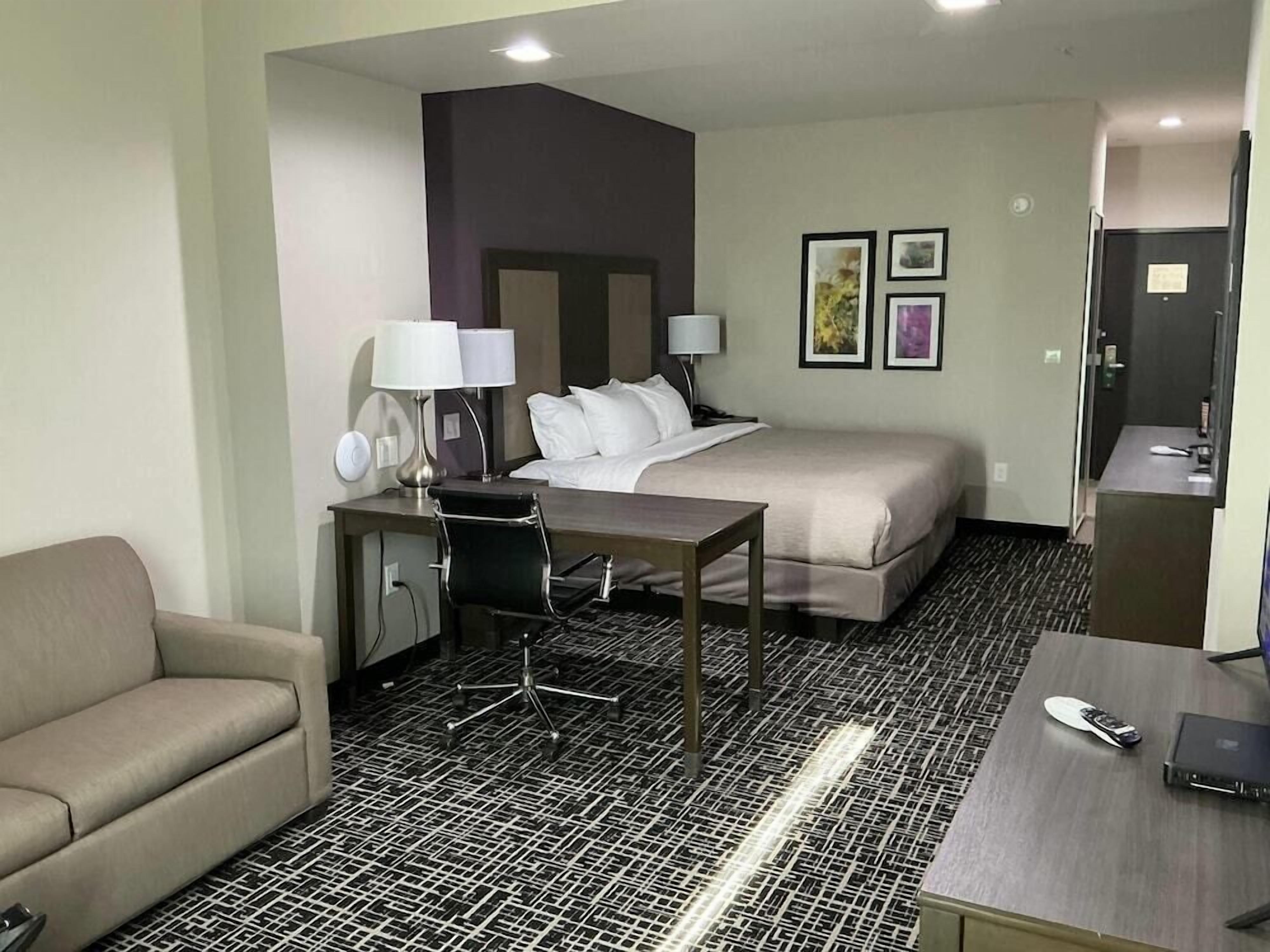 Ein Hotelzimmer mit Bett, Schreibtisch mit Stuhl, einer Sitzecke und einer kleinen Küchenzeile.