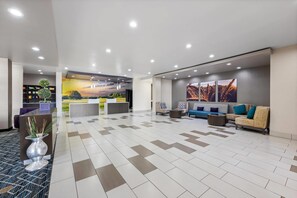 A modern hotel lobby with a reception desk, seating area, and a mural wall. - Quality Inn & Suites Colorado City, TX (Colorado City)