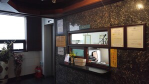Un mostrador de recepción con una pared de mármol, certificados enmarcados y una ventana con vistas.