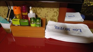 Un tocador de baño con artículos de aseo, un portalápices para cepillos de dientes y toallas.