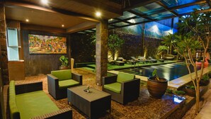A lounge area with wicker furniture, a small pool, and a mural on the wall. - Hotel L'Amore Bali (Seminyak)