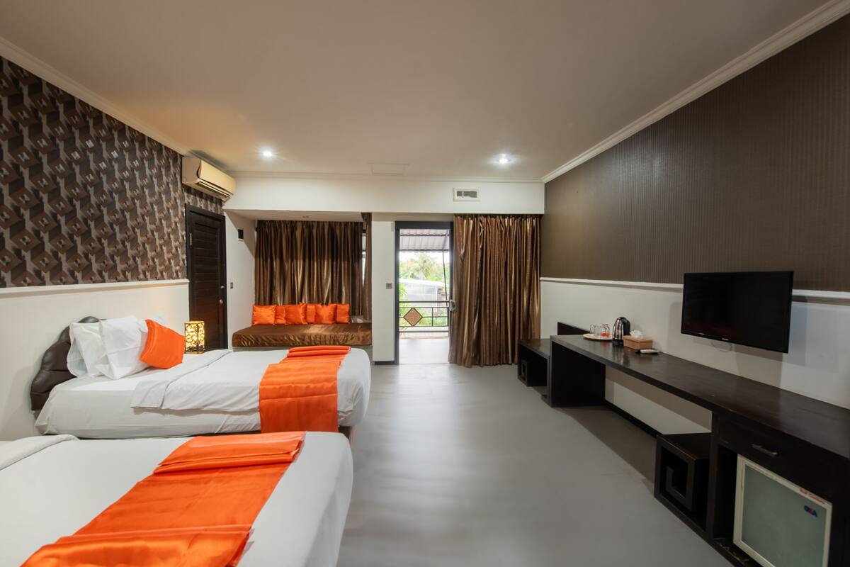 A hotel room with two beds, a desk, a TV, and a view of the outdoors.