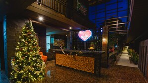 A lobby with a Christmas tree, a reception desk, and a neon heart sign. - Hotel L'Amore Bali (Seminyak)