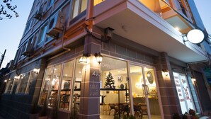 Ein mehrstöckiges Hotel mit Restaurant im Erdgeschoss, großen Fenstern und Außenbereich.