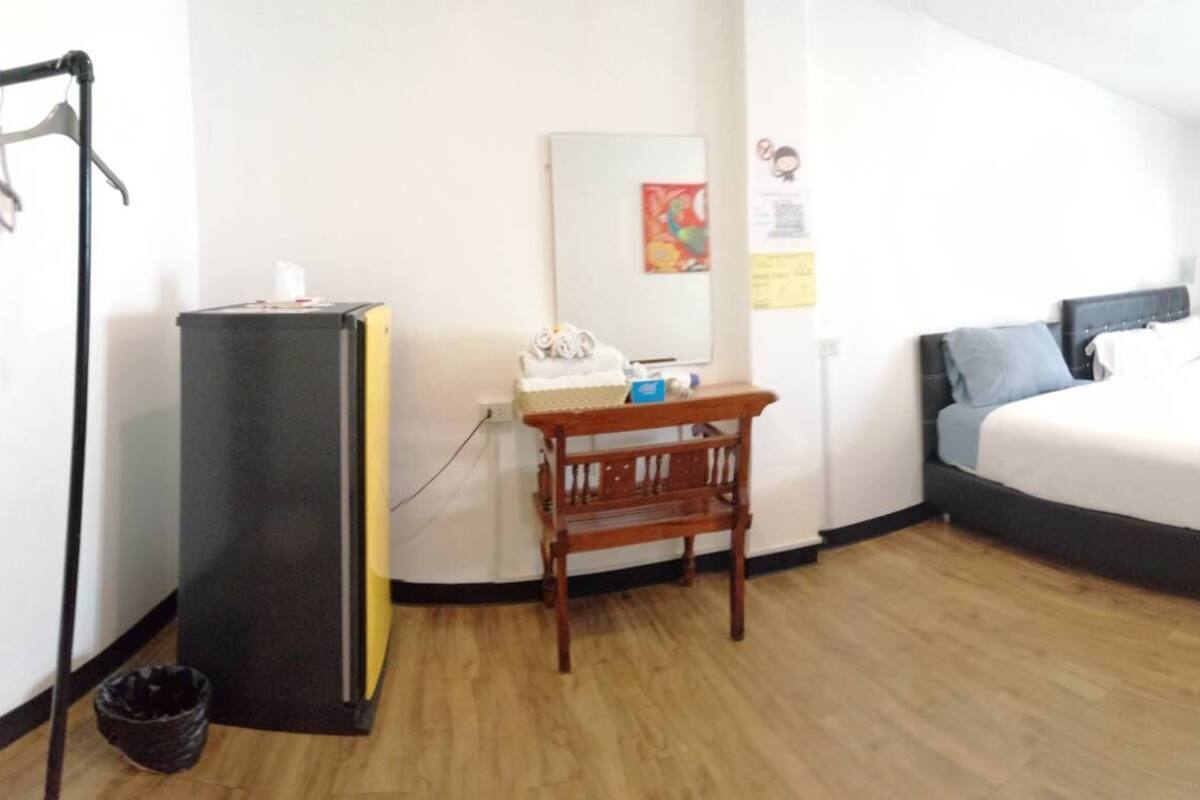 A hotel room with a bed, a desk, a chair, a mirror, a sink, and a toilet.