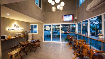 Interior de restaurante con bar, muebles de madera y una pantalla grande.
