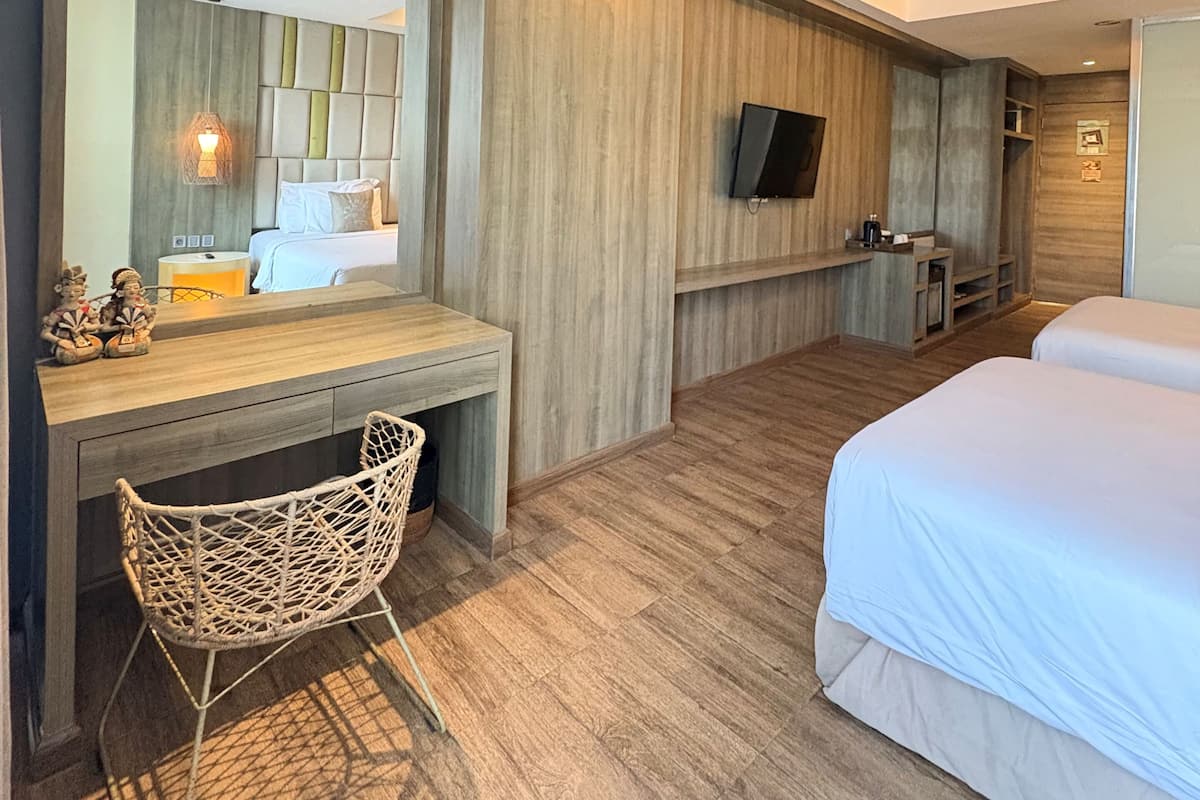 A hotel room with a bed, a desk, a chair, a TV, and a mirror.