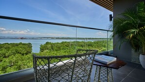 A balcony with a view of a body of water, greenery, and a distant bridge. - The Crystal Luxury Bay Resort Nusa Dua (Nusa Dua)