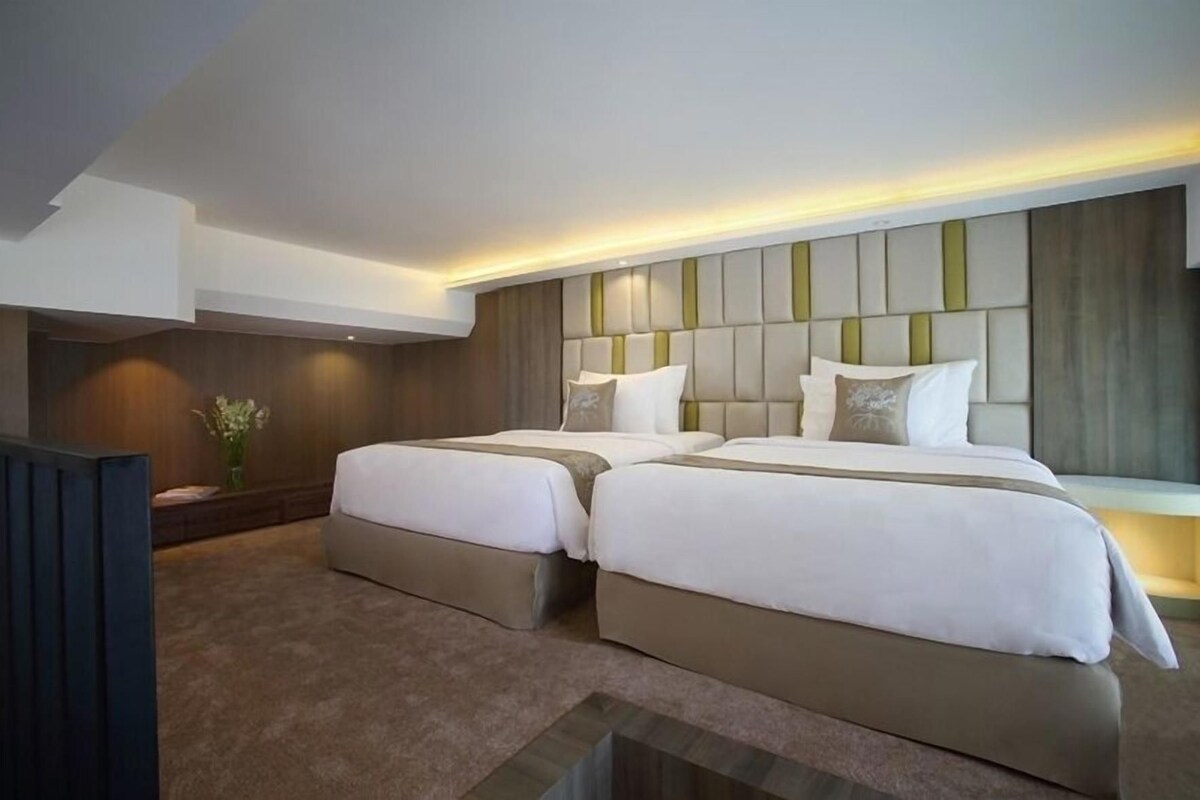 Ein modernes Hotelzimmer mit zwei Betten, einem großen Fenster und einem integrierten Fernseher.
