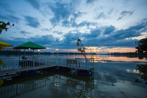 A dock with a gazebo and benches, a calm lake, and a sunset in the background.