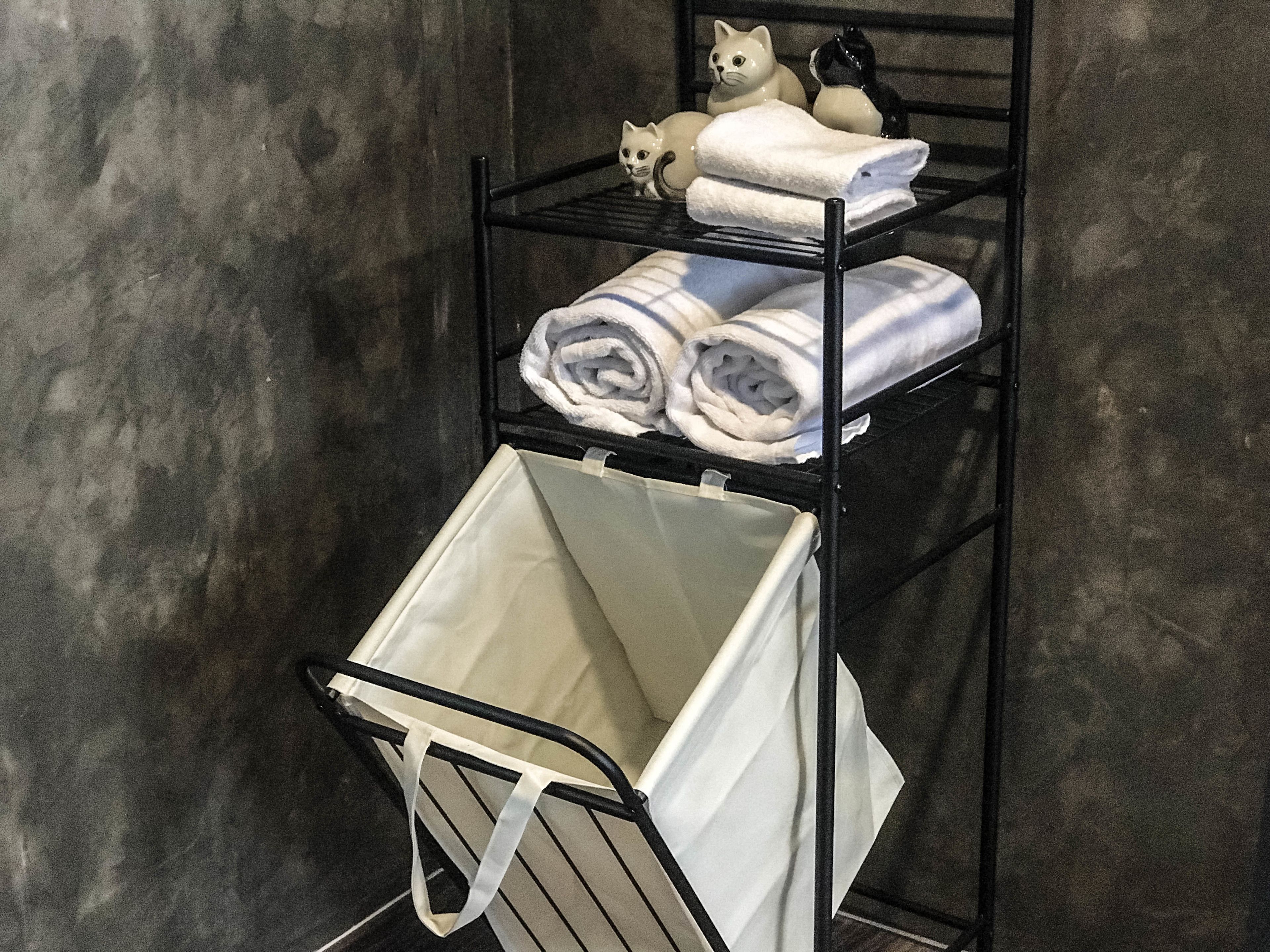 A metal shelf unit with folded towels and a white laundry basket.