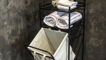 A metal shelf unit with folded towels and a white laundry basket.