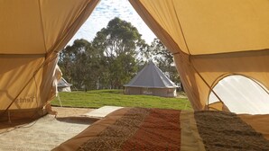 A tent with a view of a grassy area and another tent in the background.