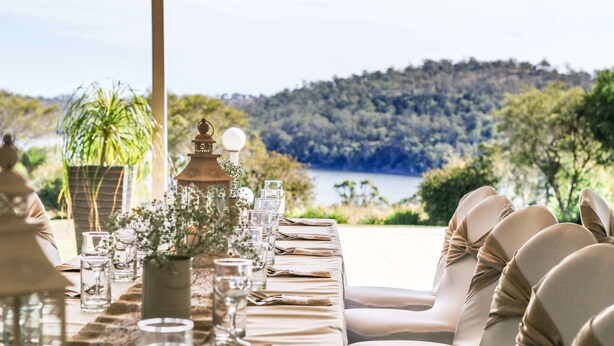 A dining table set for six with a view of a lake and forest.