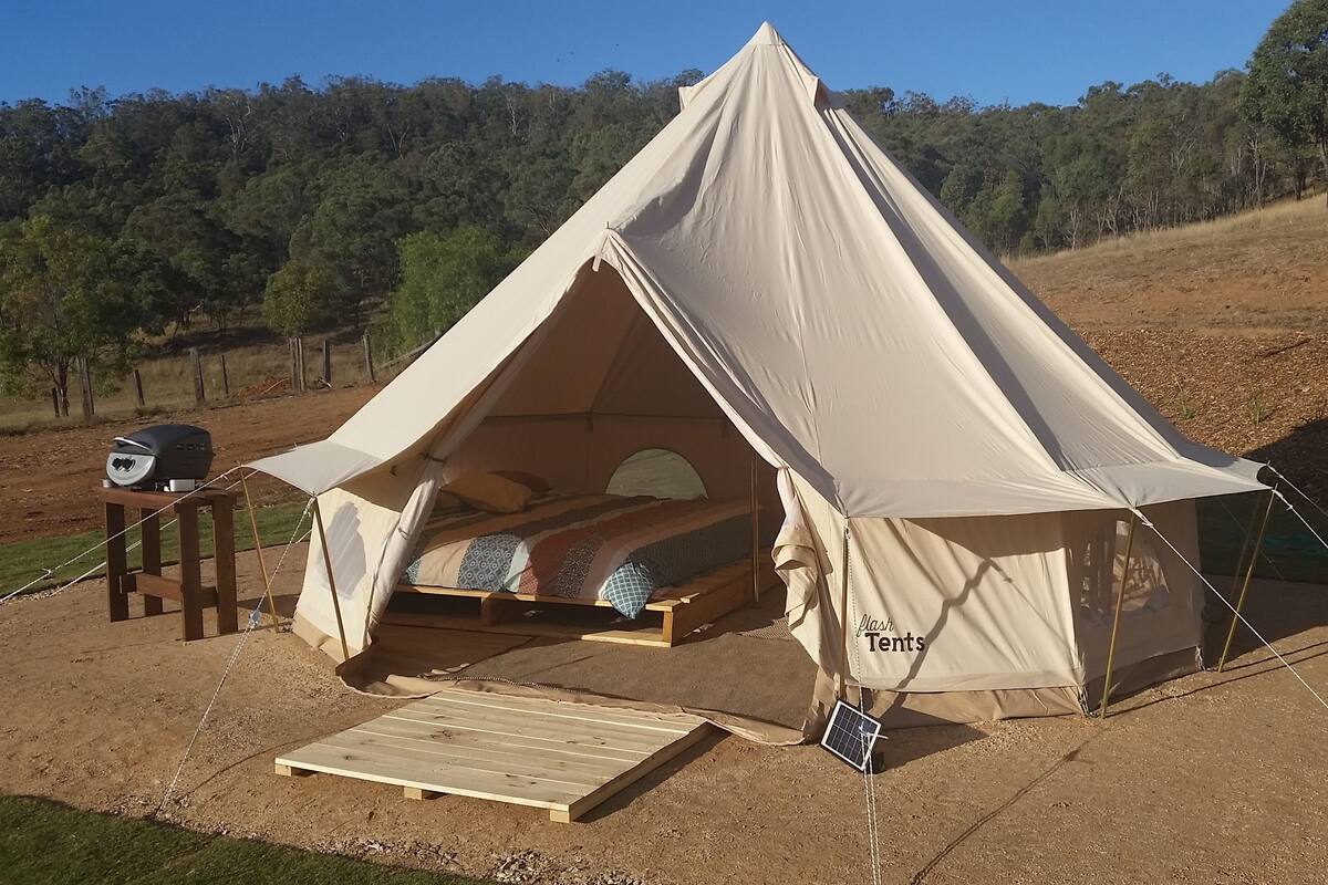A tent with a bed inside, a small table, and a solar panel.