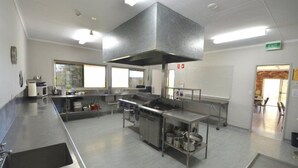 A spacious commercial kitchen with stainless steel appliances, large windows, and an exit sign.