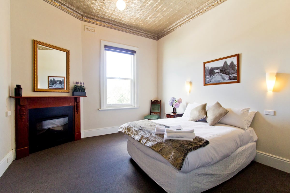 Ein Schlafzimmer mit einem großen Bett, einem Kamin, einem Fenster und einem Wandbild.