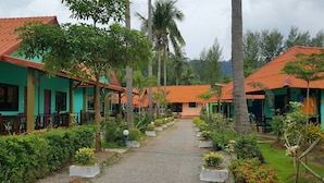 Un resort con varias construcciones tipo bungaló, un camino de grava y abundante vegetación.
