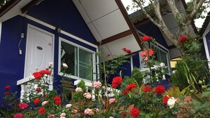 Una casa con fachada azul, marcos de ventana blancos y una pared de ladrillo.