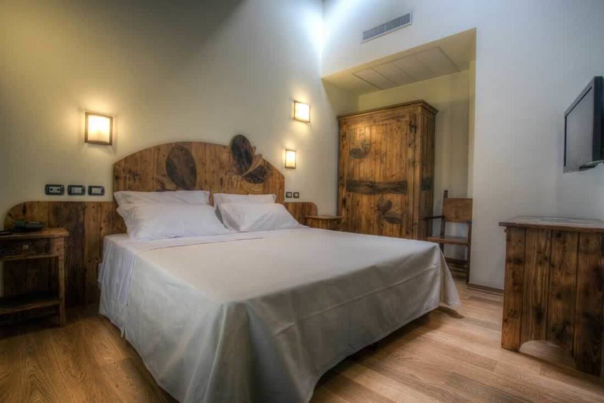 A bedroom with a large bed, wooden headboard, bedside tables, and a wardrobe.