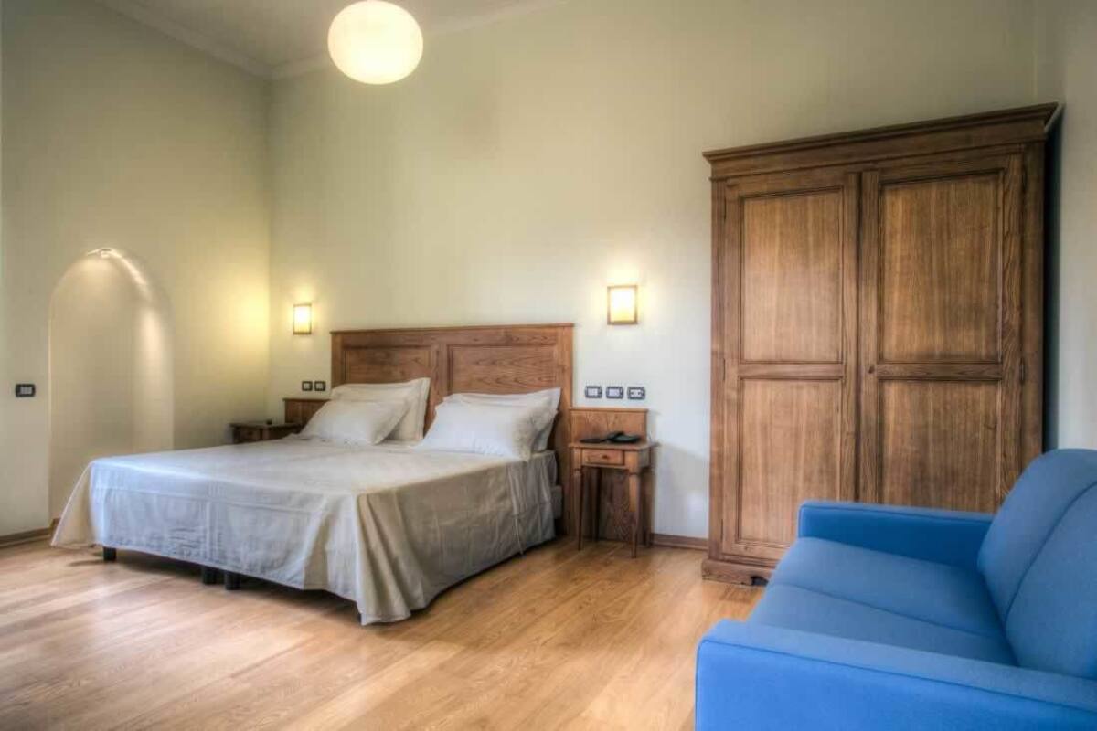 A bedroom with a bed, bedside tables, a wardrobe, and a blue chair.