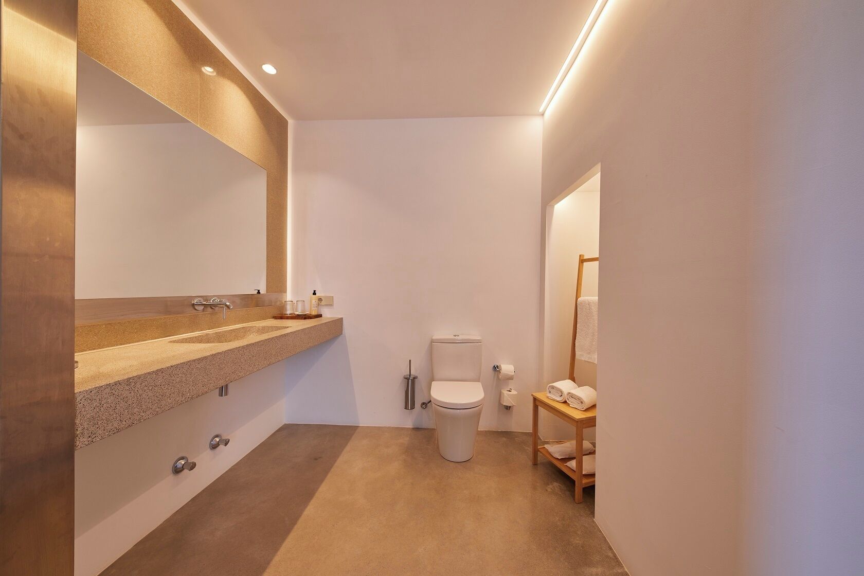 Een moderne badkamer met een grote spiegel, een wastafel en een toilet.