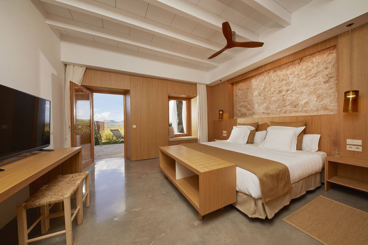 Quarto moderno com uma cama grande, uma escrivaninha e uma televisão.