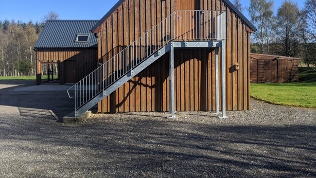 A large wooden barn with a metal staircase leading to a covered area. - Willowbarn Self-Catering Rafford (Forres)