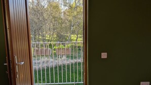 A room with a wooden door leading to a balcony with a metal railing. - Willowbarn Self-Catering Rafford (Forres)