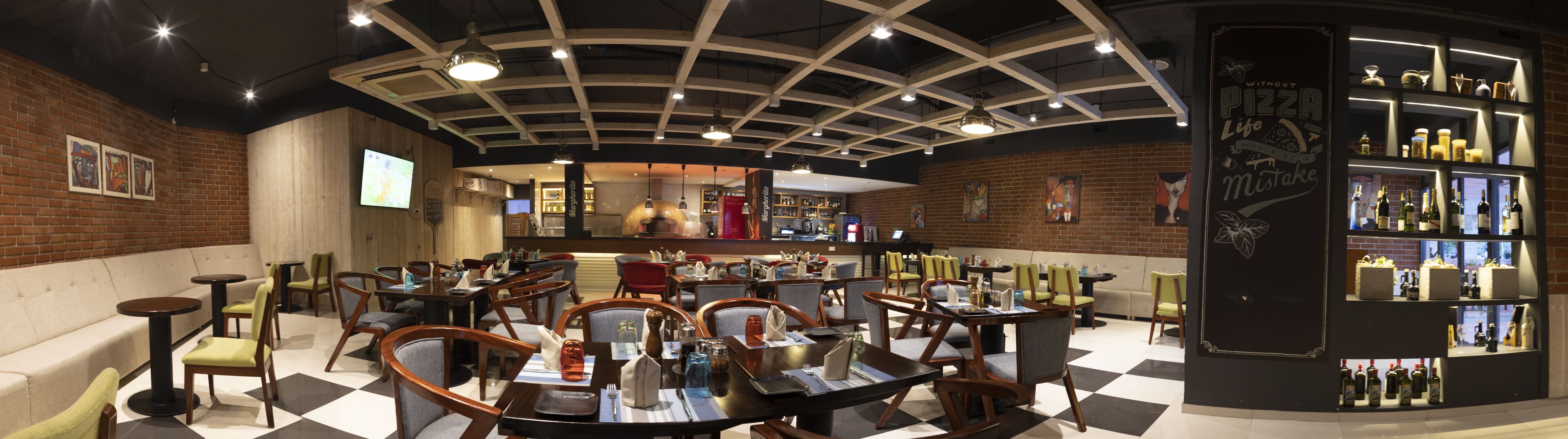A restaurant with a modern interior, featuring a mix of seating options including tables and booths, a bar area with a wine and liquor display, and a brick wall with artwork.