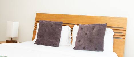 A neatly made bed with a wooden headboard, two pillows, and a patterned throw blanket.