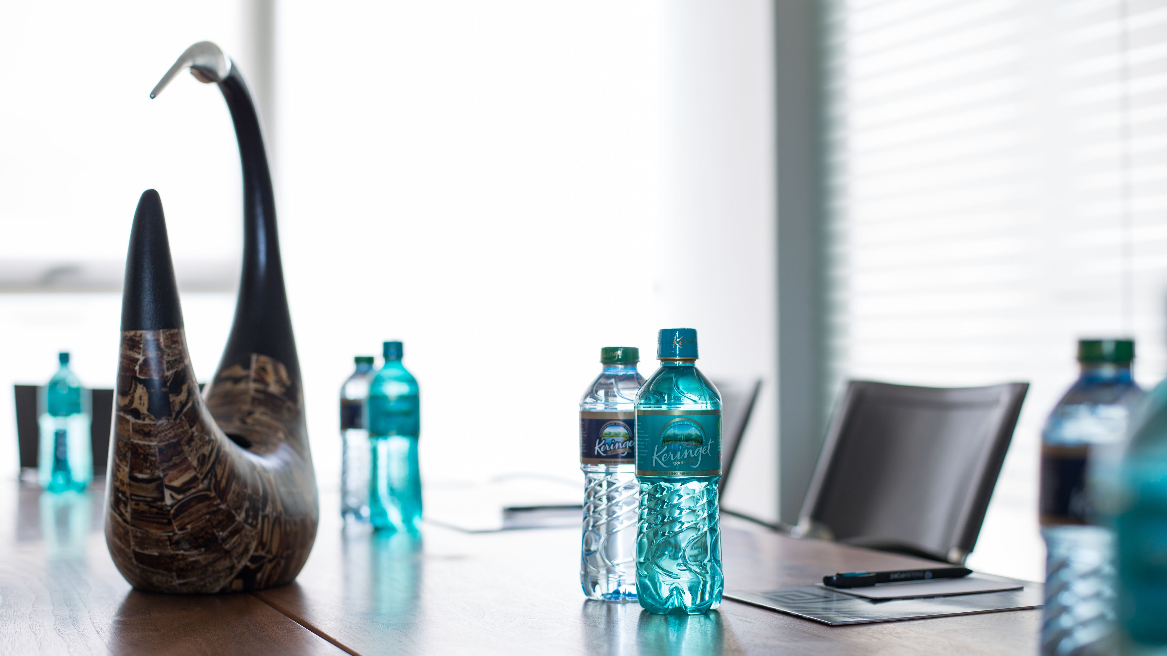 A conference table with water bottles and a decorative vase.