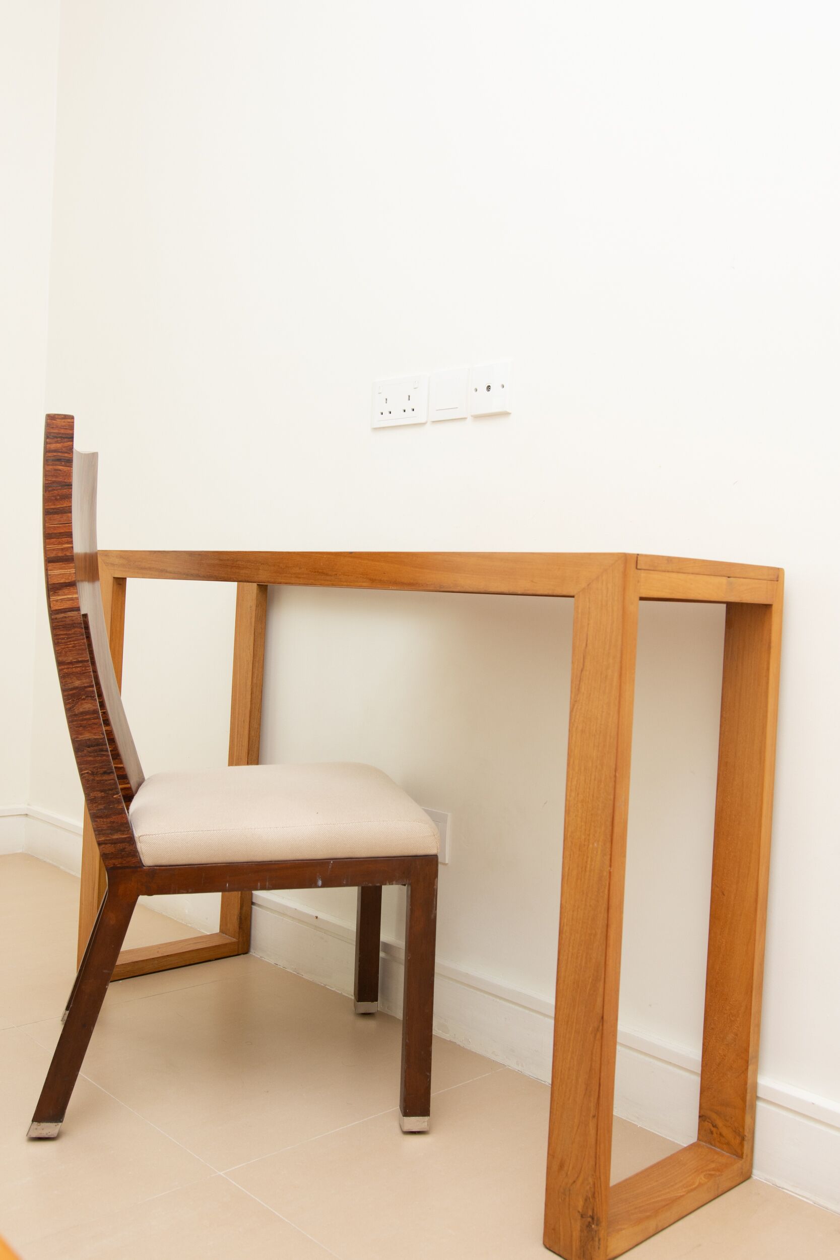 A wooden chair with a cushioned seat and backrest, positioned next to a wooden table with a simple design.