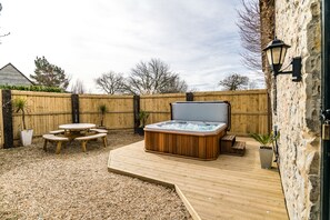 A backyard with a hot tub, wooden deck, and a stone wall. - Somerset Country Escape (Taunton)