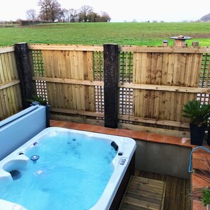 A hot tub in a backyard with a wooden fence and a grassy field in the background. - Somerset Country Escape (Taunton)