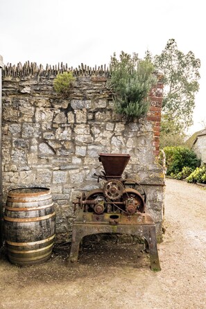 A rustic stone wall with a metal device and a wooden barrel.