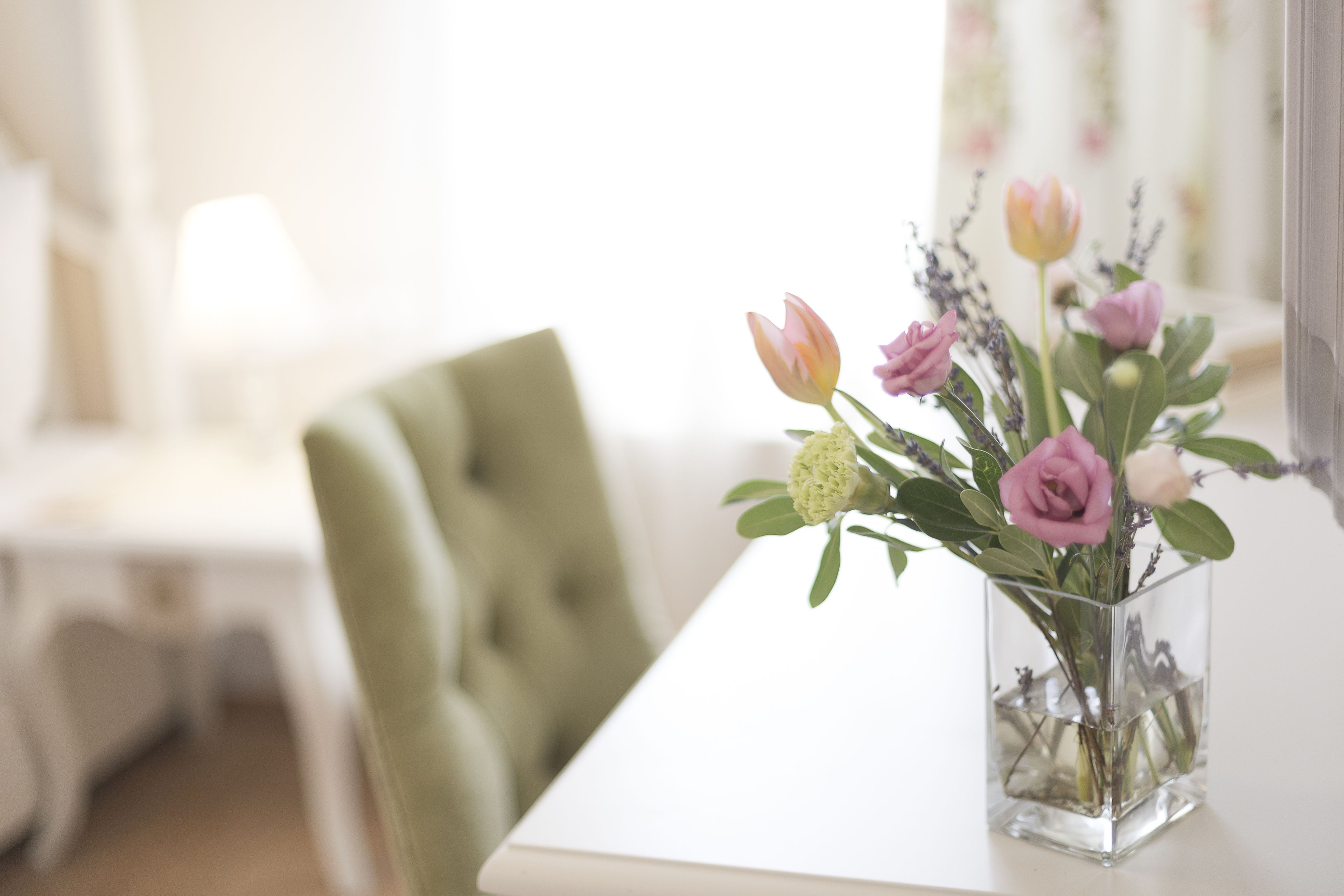 Un jarrón de vidrio transparente con flores sobre una mesa blanca.