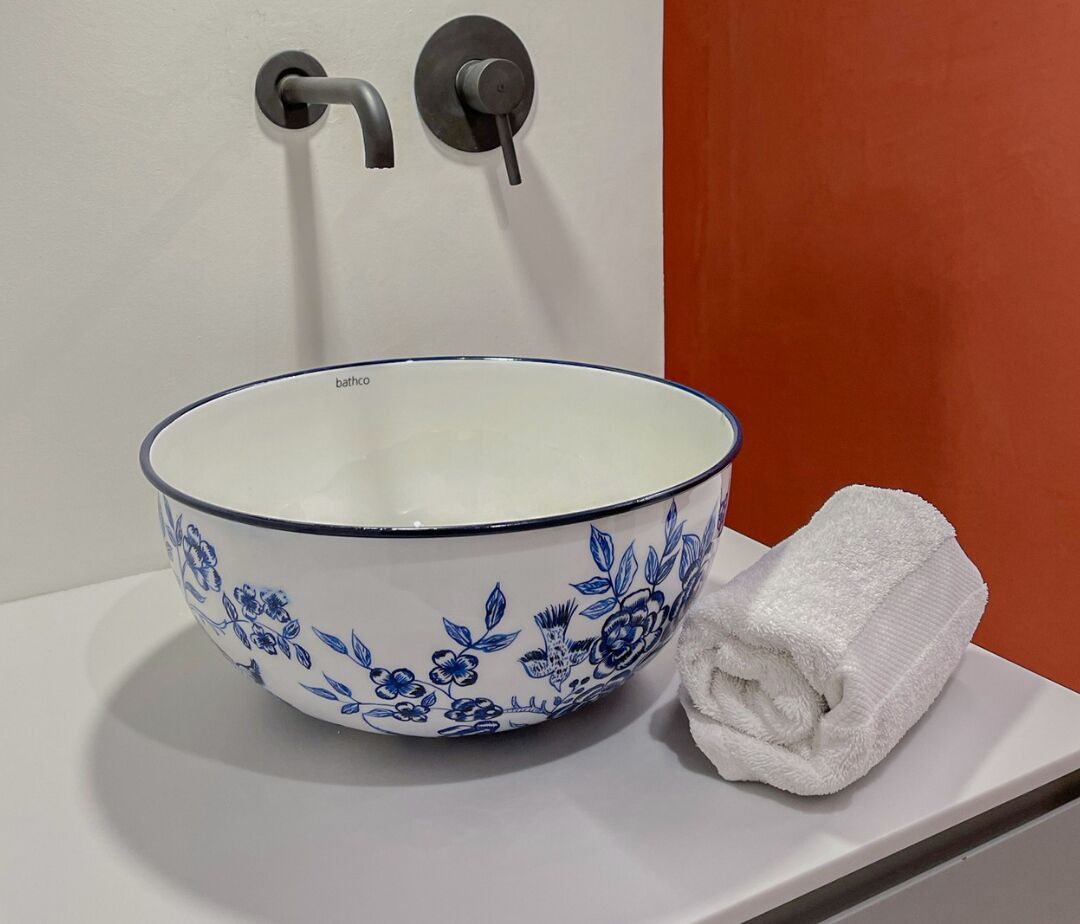 Uma pia de banheiro branca com design de flor, uma toalha e uma torneira.