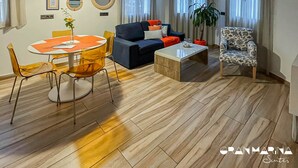 A modern living room with a round dining table, a sofa, a coffee table, and a patterned armchair. - Gran Marina Suites (Las Palmas de Gran Canaria)